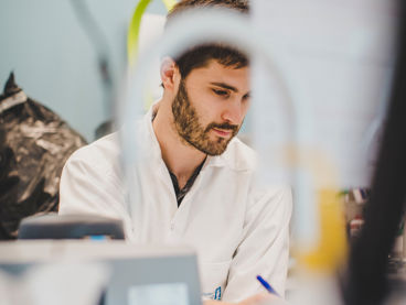 En forskare sitter vid sitt skrivbord i ett laboratorie.